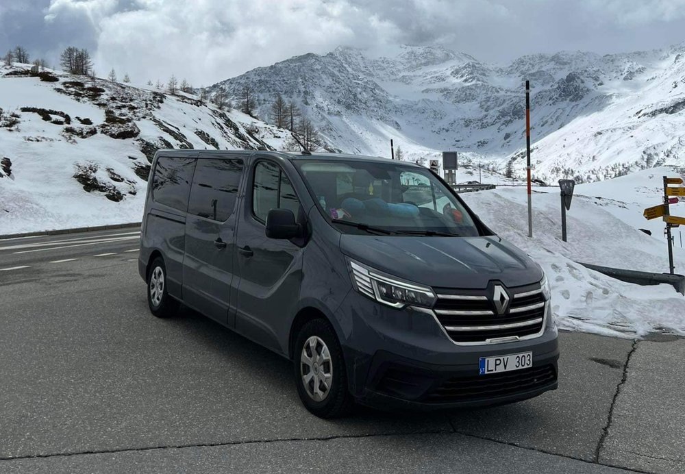 Mikroautobusas su slidėmis kalnų fone